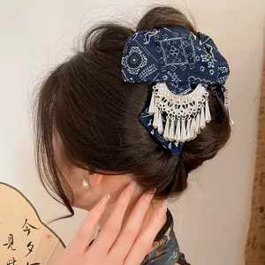Detail van een etnische blauwe batik haarklem met zilveren kwastjes in een knot.