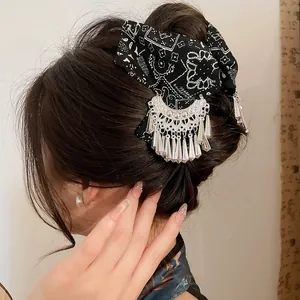 Detailopname van een etnische batik haarklem met zilveren kwastjes op gestyled haar