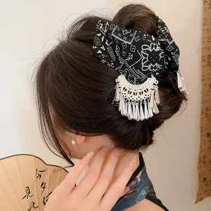 Detailopname van een etnische haarklem met een batik stoffen strik en zilveren kwastjes.