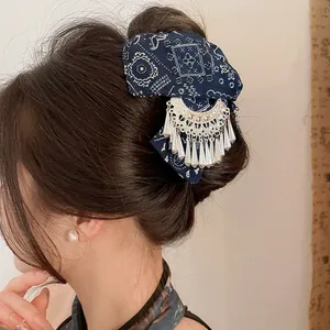 Gedetailleerd overzicht van etnische batik haarklem met zilveren kwastje op een knot