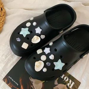 Detailed macro view of decorative resin star and shell charms on black DIY garden clogs