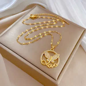 Vista detallada de un collar de mariposa dorado con un colgante 'Love' de circonita