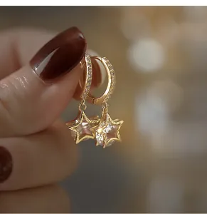 Nahaufnahme eleganter goldener Creolen mit funkelnden Sternanhängern und feinen Kristallen