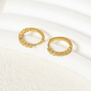 Detailaufnahme von vergoldeten 925er Silberohrringen mit schimmernden Zirkonia-Steinen.