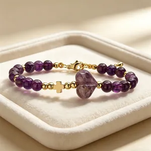 Dettaglio ravvicinato di un bracciale in ametista con croce dorata e pietra a forma di cuore