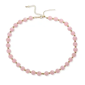 Collier élégant en perles d'acrylique rose avec espaceurs dorés sur fond blanc.