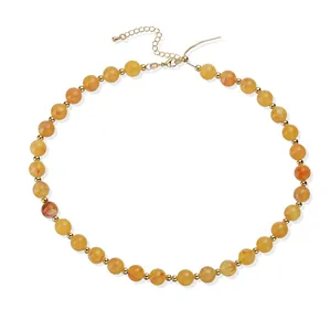 Vue détaillée d'un collier de perles en acrylique ambré avec des accents dorés pour femme.