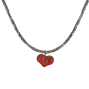 Close-up detail of a red heart pendant hanging from a dark metallic bead necklace chain