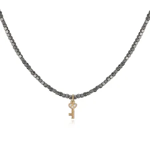 Detailed shot of a gold-plated heart key pendant on a stylish dark beaded necklace