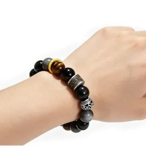 Macro view of a 10mm silver obsidian and tiger eye beaded bracelet worn on a wrist.