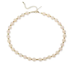 Vue détaillée de perles en acrylique crème et perles d'espacement dorées sur un collier