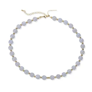 Détail de perles en acrylique bleu clair et d'espaceurs dorés sur un collier élégant