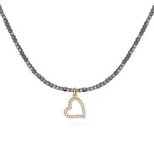 Detailed view of a heart pendant necklace featuring gray metallic beads and gold finish.