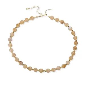Vue détaillée d'un collier en acrylique avec perles marbrées beiges et séparateurs dorés.