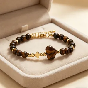 Dettaglio di un bracciale in pietra naturale occhio di tigre a cuore con ciondolo a croce