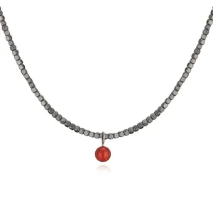 Detail view of a minimalist necklace with grey cube beads and a vibrant red bead pendant.