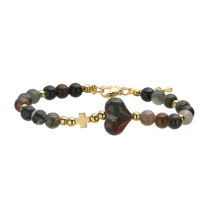 Dettaglio del bracciale in pietra naturale a cuore con croce dorata e perline.