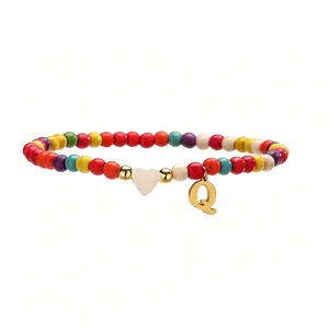 Gros plan d'une chevillère à perles colorées avec pendentif lettre Q dorée et cœur