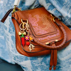 Gros plan d'un bijou de sac coloré avec charms cœur et léopard sur un sac en cuir marron