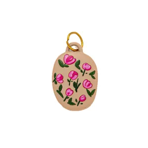 Elegant oval shoe charm featuring pink tulip floral patterns and a gold ring loop