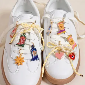 Detail view of colorful shoe charms featuring boot, sun, and heart pendants on white sneakers