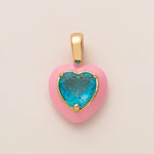 Primer plano detallado de un colgante de corazón rosa con una gema azul brillante.
