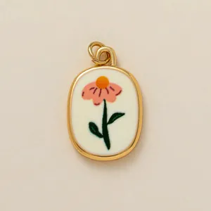 Close-up of elegant oval gold pendant featuring an embroidered pink flower design