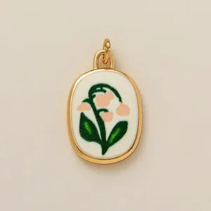 Detailed view of an oval gold pendant featuring a delicate pink lily of the valley.