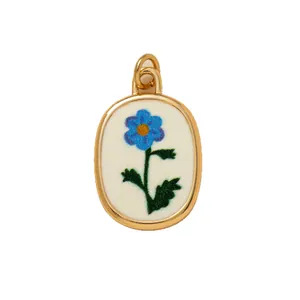 Elegant gold-rimmed oval pendant featuring a delicate blue flower print on white background