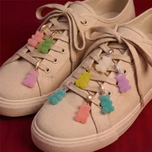 Detailed macro view of colorful resin gummy bear shoe charms clipped onto beige sneakers laces