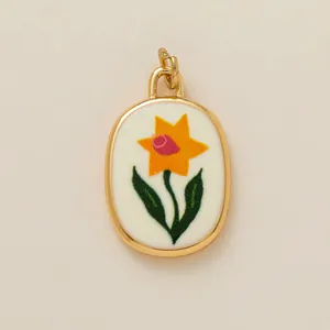 Detailed macro shot of an oval gold-plated pendant featuring a yellow narcissus flower