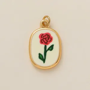 Close-up of an elegant oval gold pendant with a red rose illustration on a white background