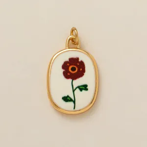 Vintage oval gold-toned pendant with a deep red flower motif and green stem.