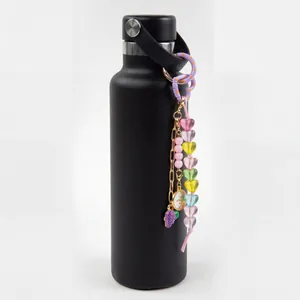 Colorful heart bead keychain with grape and sun charms displayed on a black bottle