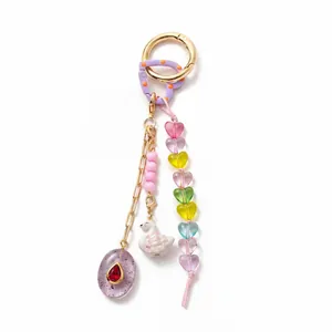 Detailed view of a colorful bag charm with heart beads, a swan, and a purple pendant.