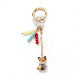 Close-up of cute porcelain fox charm and colorful beads on 18K gold plated keychain