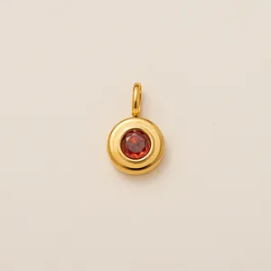 Close-up detail of a gold-plated stainless steel pendant with a round red zircon