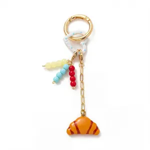 Detailed view of DIY fashion keychain featuring colorful beads and cute croissant bag charm