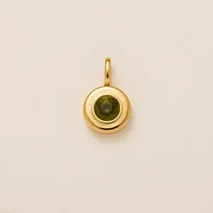 Close-up of a round 18K gold plated pendant featuring a faceted green birthstone.