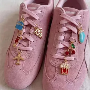 Vue détaillée de breloques en émail colorées attachées aux lacets de baskets en daim rose