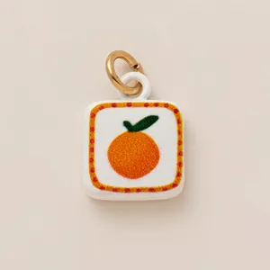Detail view of square ceramic orange fruit charm for DIY jewelry or shoe accessory