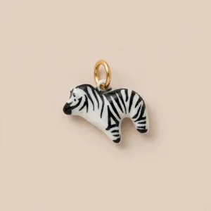 Macro detail of a hand-painted ceramic zebra pendant charm with a gold jump ring