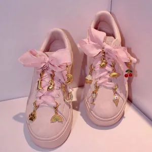 Primer plano de adornos dorados para zapatos con conejitos y arcoíris en zapatillas rosas