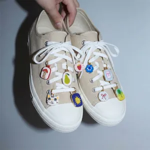 Detail of colorful DIY cartoon shoe charms attached to beige canvas sneakers