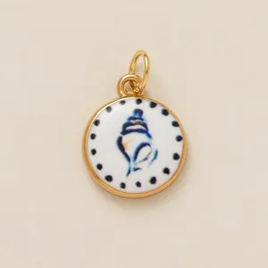 Vista detallada de un amuleto circular chapado en oro con diseño de caracola azul