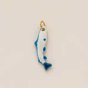 Dettaglio di un ciondolo a forma di pesce in smalto blu e bianco con anello dorato