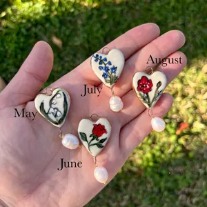 Close-up detail of four floral birth month heart pendants with elegant baroque pearls