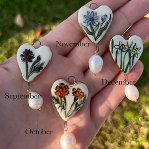Detail view of heart-shaped enamel birth flower pendants with baroque pearl drops