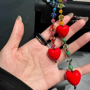 Fashionable colorful beaded bag chain with large vibrant red heart acrylic pendants