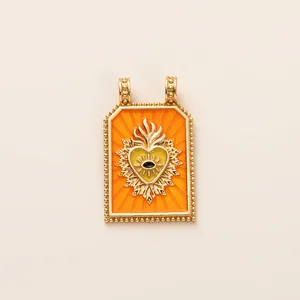 Close-up detail of a vintage style orange enamel Tarot heart pendant with golden evil eye motif